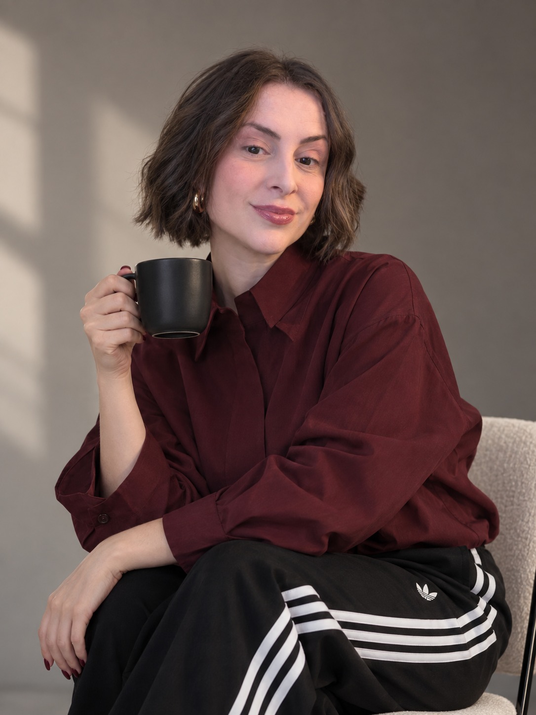 Raquel Mendonça segurando uma xícara preta, com camisa vinho